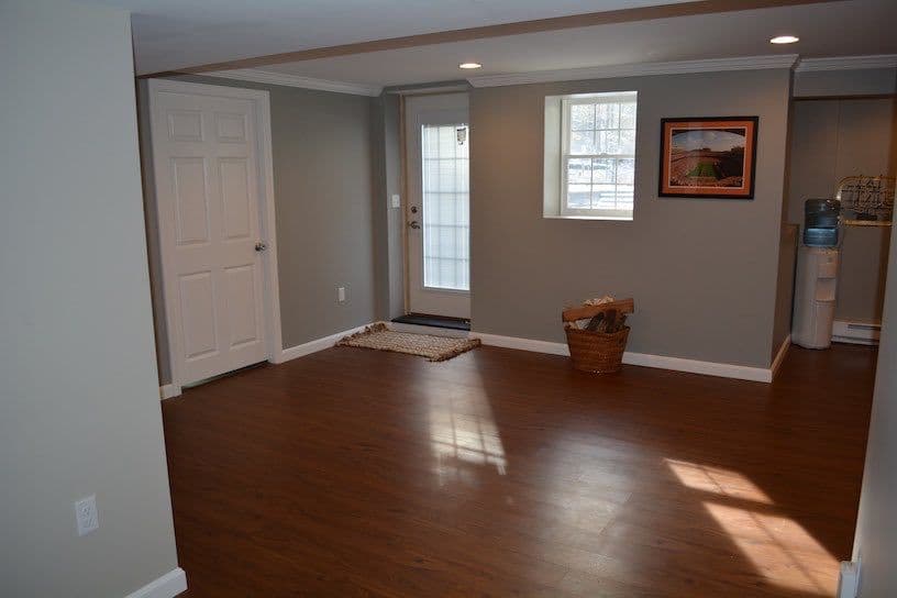 Spacious, well-lit room with hardwood floors, door to outside, and decorative wall art.