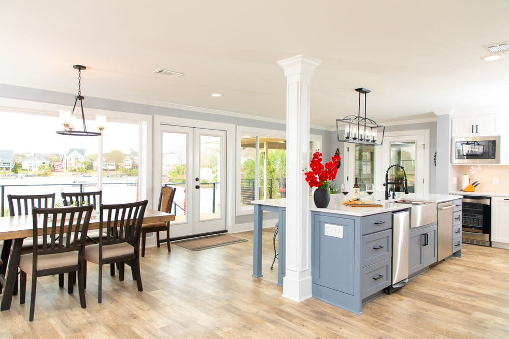 Modern kitchen and dining area with lake view, hardwood floor, and vibrant red floral arrangement.
