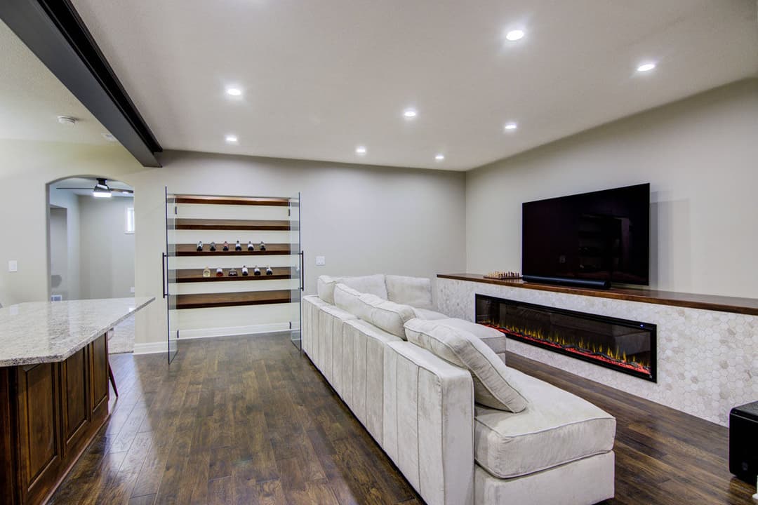 Modern basement living space with plush white sofa, fireplace, and sleek entertainment area.