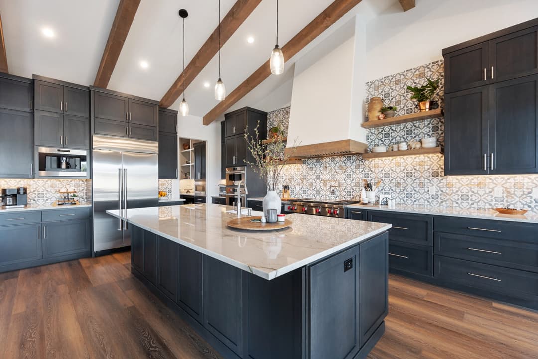 Modern kitchen with dark cabinetry, marble island, and stylish tile backsplash.