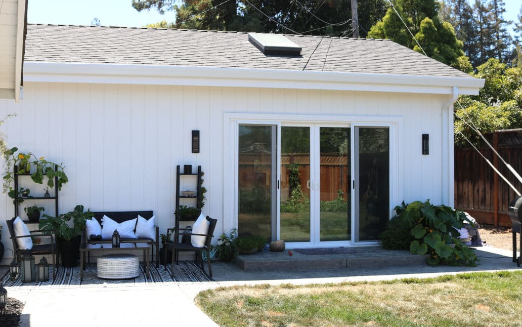 Modern backyard patio with sliding glass doors, seating area, and garden. Bright and inviting space.